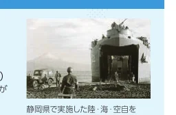 富士山を背景に、上陸用舟艇が海岸に乗り上げている様子を捉えた白黒写真。