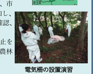 森の中で防護服を着用した人々が電気柵の設置演習を行っている様子を写した写真