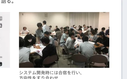 会議室で多くの人々がテーブルを囲んで座り、話し合っている様子。